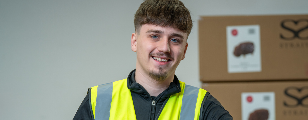 Young male learner wearing a high vis jacket inside a British Hear Foundation shop