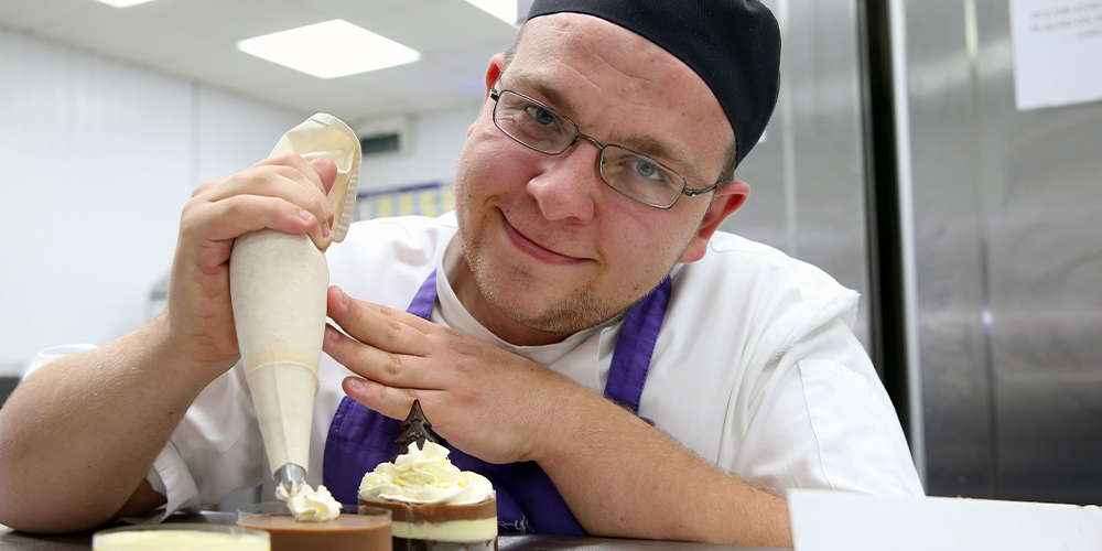 Catering apprentice icing a cake at Terry's Patisserie