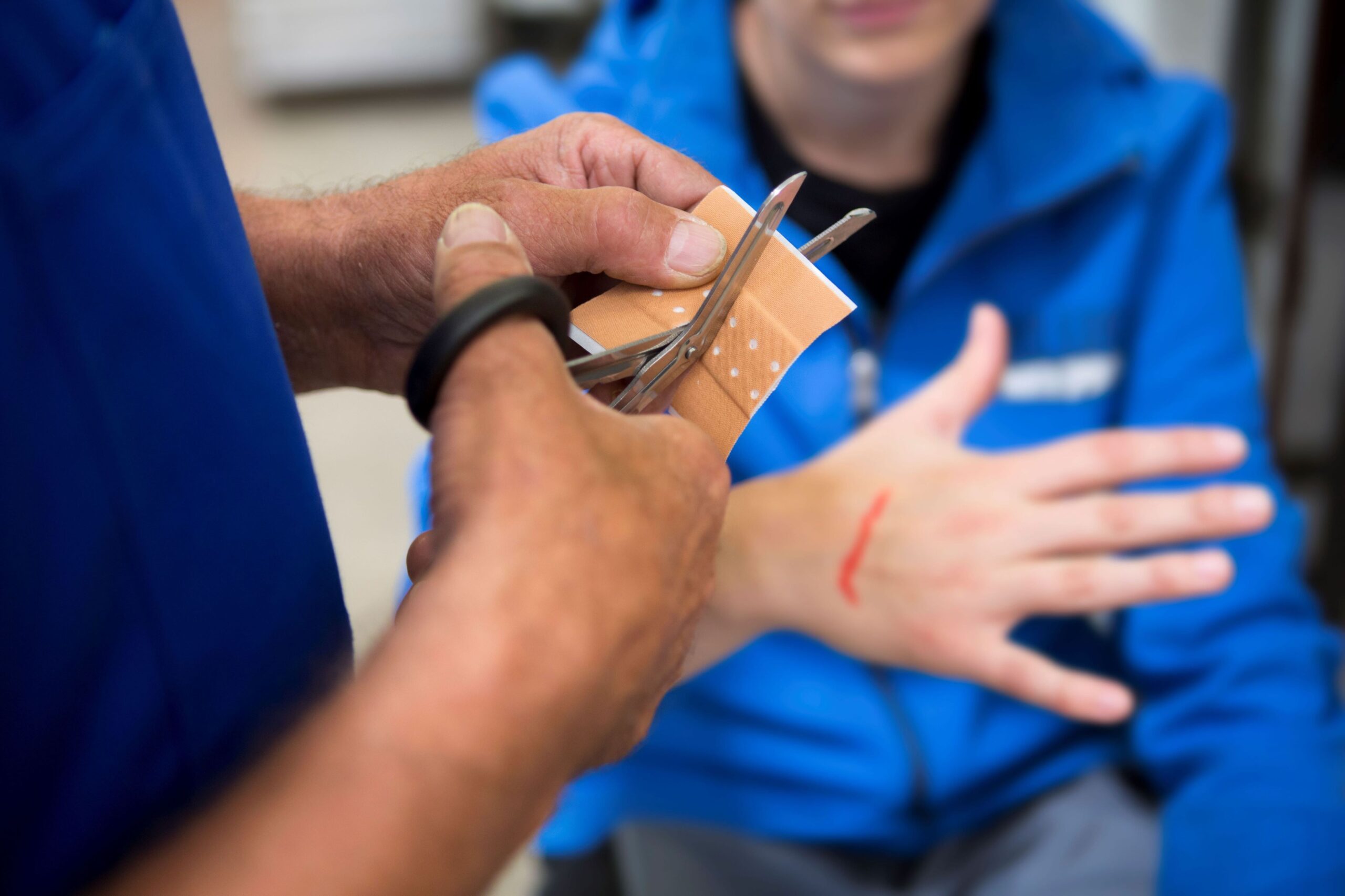 Health and Safety training. Tutor demonstrating first aid techniques and bandaging a cut on a hand.